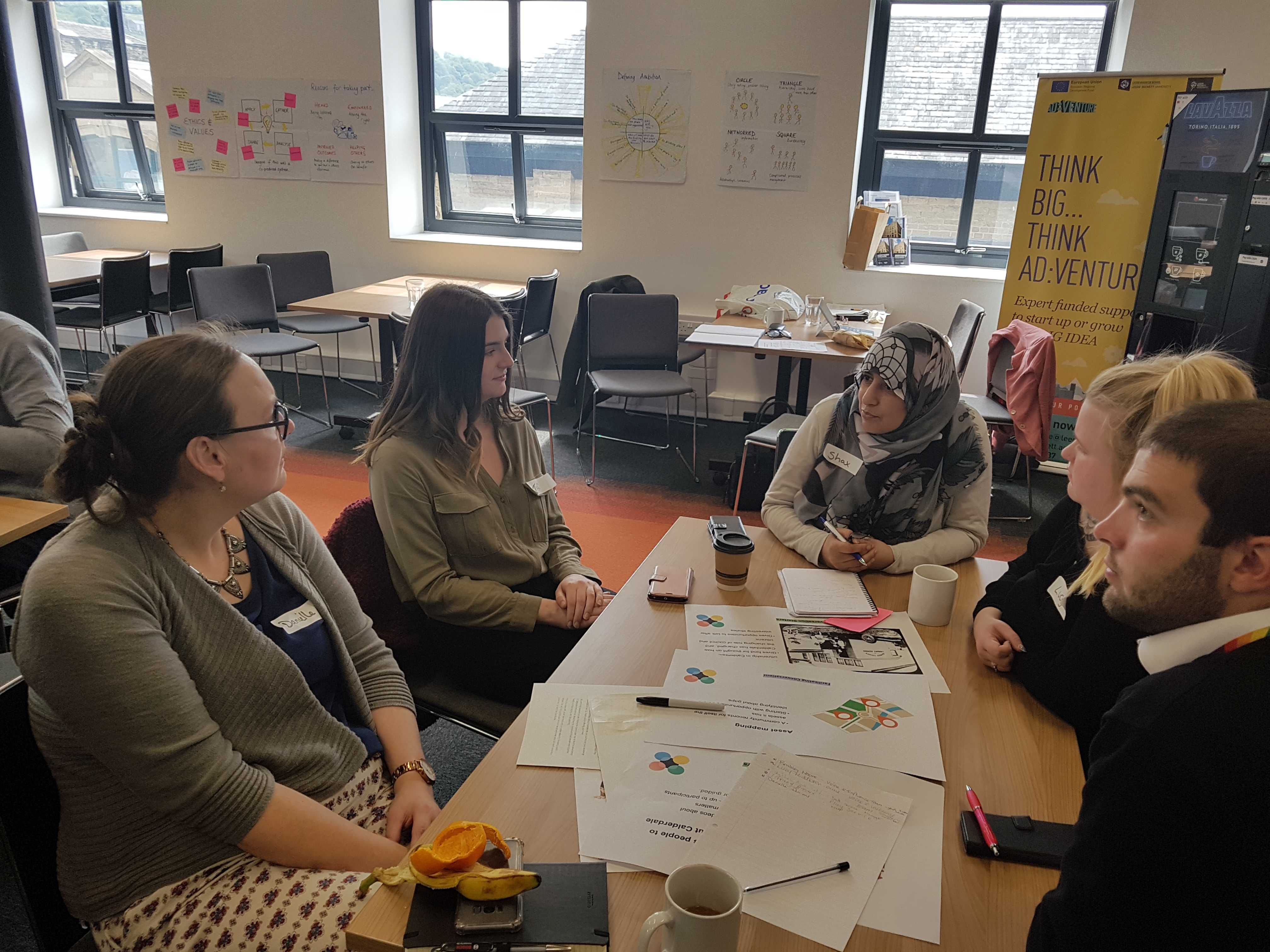 A group of five people working together around a table during a prototyping workshop